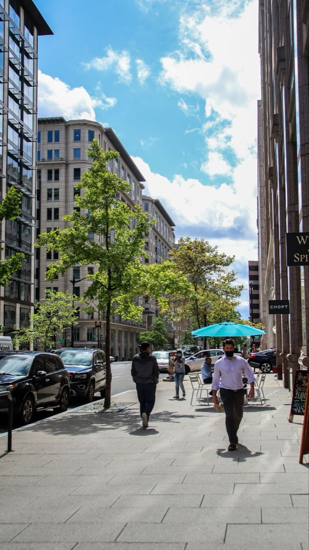 Environment reference: a sunlit downtown plaza sidewalk with glass buildings and stone planters