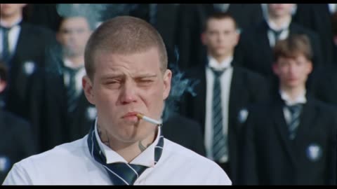 Frame from the original Storm music video: the lead smoking in front of a crowd of schoolboys