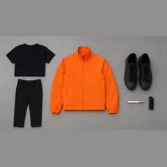 Flat-lay: orange shell jacket, black tee and trousers, black sneakers, a cigarette and lighter
